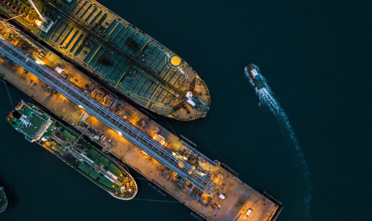 Aerial view tanker ship vessel unloading at port at night, Global business logistic import export oil and gas petrochemical with tanker ship transportation oil from dock refinery.